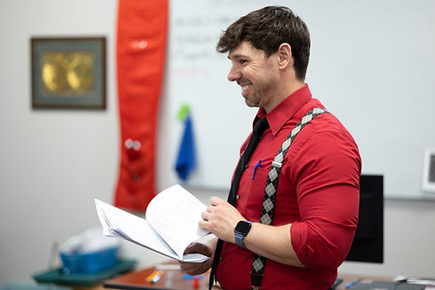 Man in a red shirt flipping through papers.