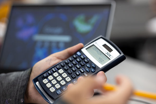 Hand holding calculator with 30x display. Students are using calculator at school.